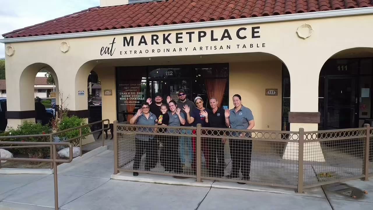 The EAT Marketplace team waving outside the storefront in Old Town Temecula